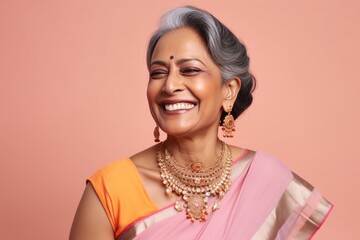 Wall Mural - Medium shot portrait of an Indian woman in her 50s wearing bindi and traditional jewelry in a colorful background