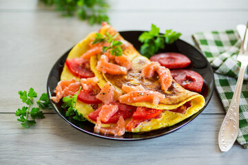 Wall Mural - Fried omelette with tomatoes, vegetables and pieces of lightly salted red fish.