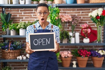 Canvas Print - African american woman working at florist holding open sign afraid and shocked with surprise and amazed expression, fear and excited face.