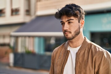 Wall Mural - Young hispanic man with relaxed expression standing at street