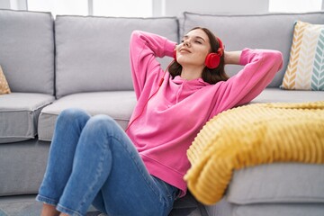 Wall Mural - Young woman listening to music sitting on floor at home