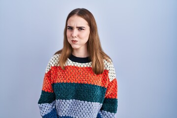 Poster - Young hispanic girl standing over blue background puffing cheeks with funny face. mouth inflated with air, crazy expression.