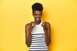 © Asier - Vibrant African woman, white tank-top, yellow studio, upset screaming with tense hands.