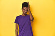 © Asier - African woman in violet tee, yellow studio scene, forgetting something, slapping forehead with palm and closing eyes.