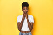 © Asier - African woman, white tee, short hair, yellow studio, doubting between two options.