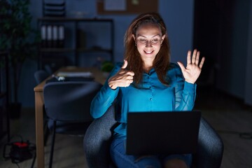 Sticker - Brunette woman working at the office at night showing and pointing up with fingers number six while smiling confident and happy.