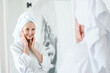 Focus on mirror reflection of smiling mid age woman touching face