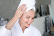 © brizmaker - Smiling middle age woman with towel on head after washing hair