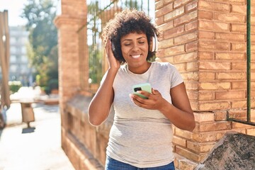 Poster - African american woman listening to music standing at street