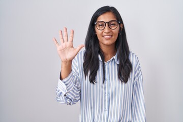 Sticker - Young hispanic woman wearing glasses showing and pointing up with fingers number five while smiling confident and happy.