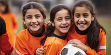 Smiling Young Girls In Football Kit Holding A Ball, Enjoying Playing Soccer With Friends