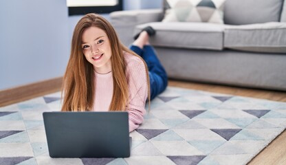 Canvas Print - Young caucasian woman using laptop lying on floor at home