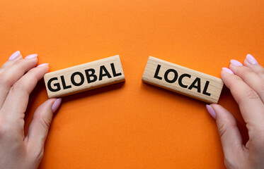 Global and Local symbol. Concept word Global and Local on wooden blocks. Businessman hand. Beautiful orange background. Business and Global and Local concept. Copy space