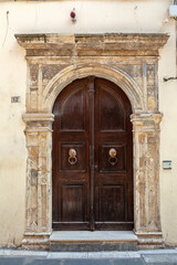 Old weather wooden door with stone arched lintel at an abandoned old mansion in Old Town of Rethymno, in Crete island, Greece, Europe. 