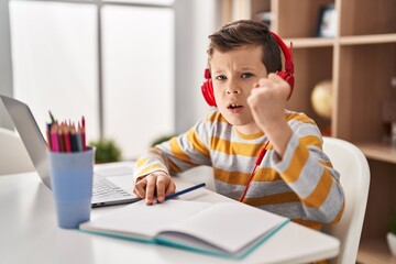 Wall Mural - Young caucasian kid doing homework at home annoyed and frustrated shouting with anger, yelling crazy with anger and hand raised