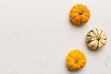 Autumn Composition Of Little Orange Pumpkins On Colored Table Background. Fall, Halloween And Thanksgiving Concept. Autumn Flat Lay Photography. Top View Vith Copy Space
