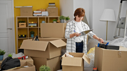 Poster - Middle age woman smiling confident reading clipboard checking at new home