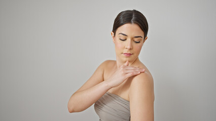 Poster - Young beautiful hispanic woman applying lotion on shoulder over isolated white background