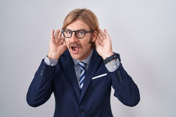 Sticker - Caucasian man with mustache wearing business clothes trying to hear both hands on ear gesture, curious for gossip. hearing problem, deaf