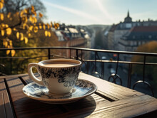 Fotografía de una taza de café en la barandilla de un balcón, con vista a una concurrida mañana otoñal en la ciudad.