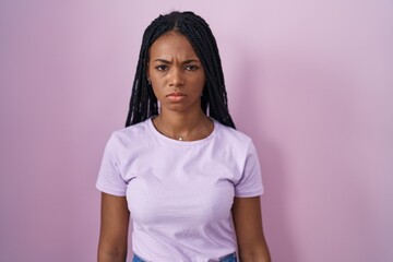 Sticker - African american woman with braids standing over pink background skeptic and nervous, frowning upset because of problem. negative person.