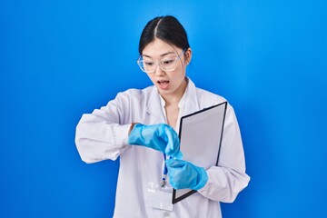 Sticker - Chinese young woman working at scientist laboratory looking at the watch time worried, afraid of getting late