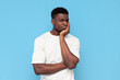 displeased young guy african american in a white t-shirt is sad and bored on blue isolated background