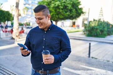 Canvas Print - Young latin man using smartphone drinking coffee at street