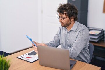 Poster - Young hispanic man business worker using touchpad and laptop at office