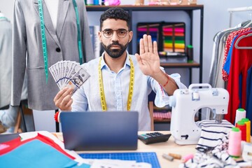 Poster - Hispanic man with beard dressmaker designer holding dollars with open hand doing stop sign with serious and confident expression, defense gesture