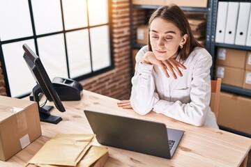 Poster - Young caucasian woman ecommerce business worker sitting on table with serious expression at office