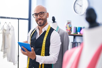 Canvas Print - Young bald man tailor smiling confident using touchpad at tailor shop