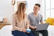 © Krakenimages.com - Man and woman mother and son drinking coffee using laptop at bedroom