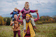 © Halfpoint - Happy parents with their little kids on piggyback at autumn walk.