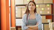 © Krakenimages.com - Young beautiful hispanic woman ecommerce business worker standing with arms crossed gesture and serious face at office