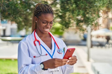 Poster - African american woman doctor smiling confident using smartphone at park