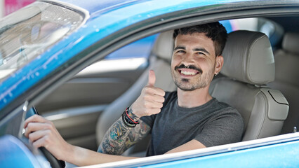 Wall Mural - Young hispanic man driving car doing ok gesture with thumb up at street