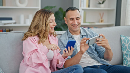 Canvas Print - Man and woman couple using smartphones sitting on sofa at home