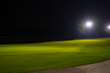 Beautiful dark night view of the golf course, Bunkers sand and green grass, garden background In the light of the spotlight underexposure view.