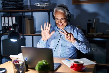 Wall Mural - Hispanic senior man wearing call center agent headset at night showing and pointing up with fingers number seven while smiling confident and happy.