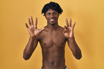 Poster - Young african man with dreadlocks standing shirtless showing and pointing up with fingers number eight while smiling confident and happy.