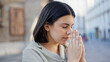 © Krakenimages.com - Young beautiful hispanic woman praying with closed eyes in the streets of Vienna
