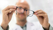© EKKAPON - Male optician and optometrist, background of shop window with different models of glasses holding glasses in hand checking glasses eye care concept