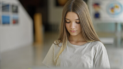 Poster - Young beautiful girl sitting on table with serious face at library