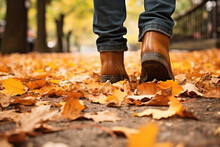 Pair Of Stylish Boots Crunching Through A Carpet Of Fallen Leaves On A Sidewalk