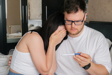 worried couple looking at positive pregnancy test