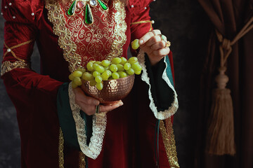 Wall Mural - Closeup on medieval queen in red dress with plate of grapes