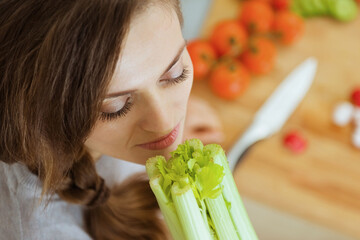 Wall Mural - Happy young woman enjoying fresh celery in modern kitchen