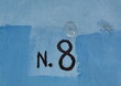 N. 8. Numéro huit. inscription peinte en noir sur mur bleu.