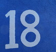 18. numéro 18. bleu pale sur mur bleu foncé.